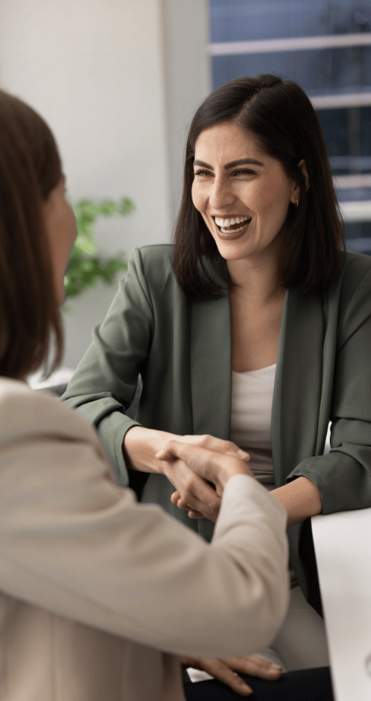 Business Woman Shaking Hands and Smiling at a Desk